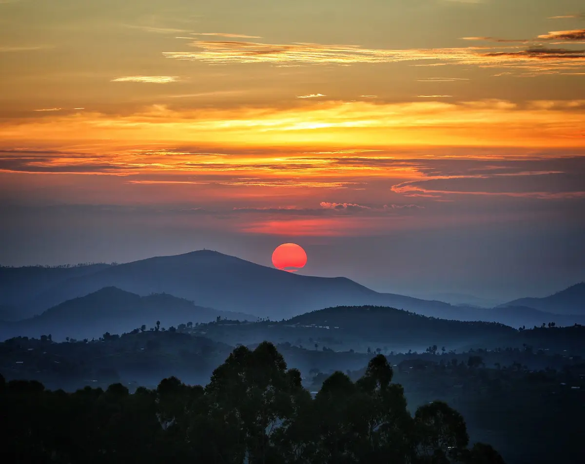 Red sun setting over layered forested ridges at Nyungwe